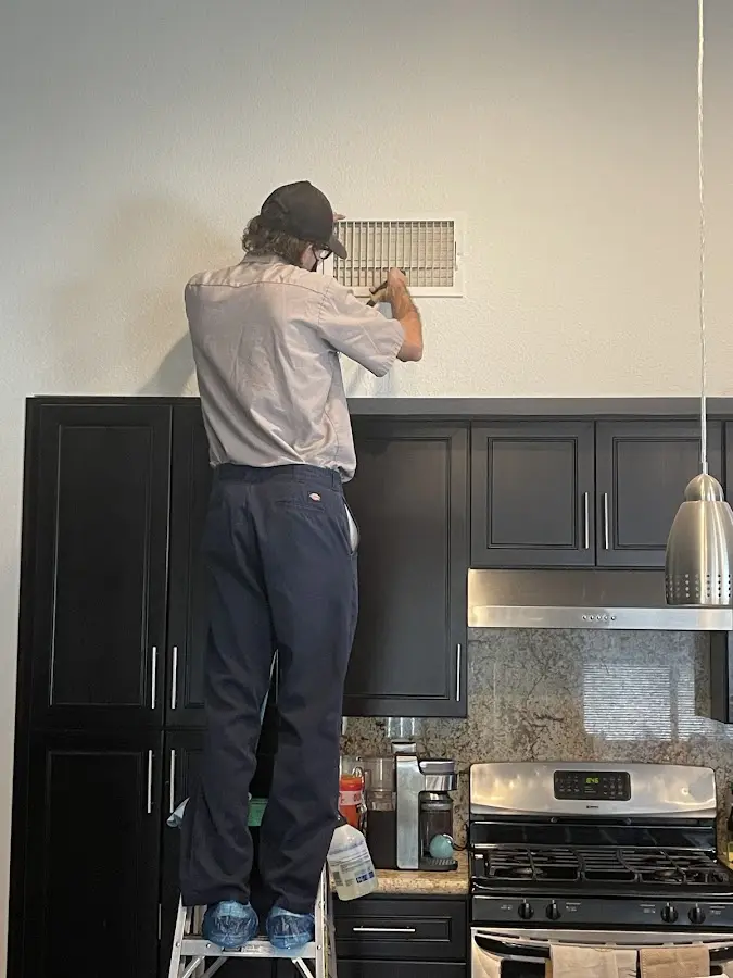 Technician inspecting an air vent during HVAC service in Bossier City